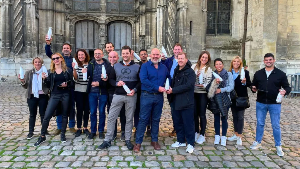 Clôture du Rallye gourmand Lyon avec une équipe réunie devant un monument, célébrant l’activité avec leurs bouteilles-récompenses.