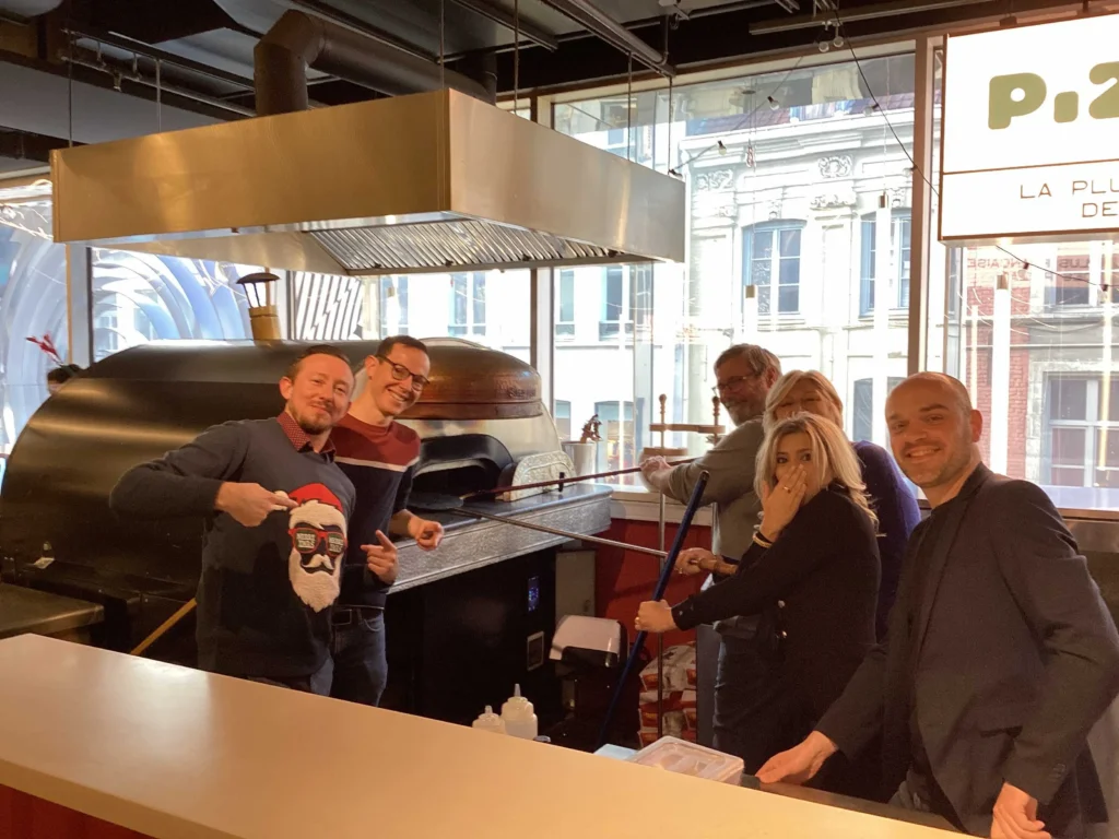 Participants du Rallye gourmand Lyon en activité culinaire, préparant une pizza dans un atelier convivial entre collègues.