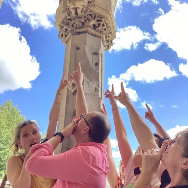 Équipe en pleine énigme culturelle lors du Rallye gourmand Lyon, levant le doigt vers un détail architectural à identifier.