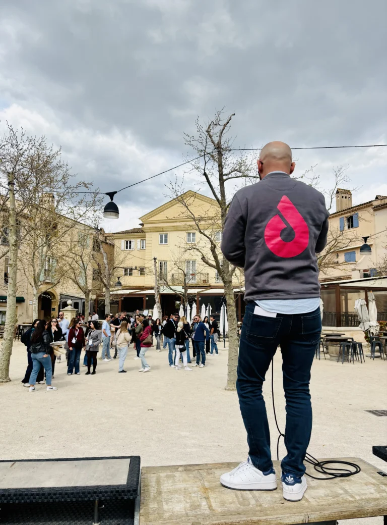 Animateur Dotmap lançant un jeu de piste entreprise devant un grand groupe de collaborateurs en séminaire d'entreprise original