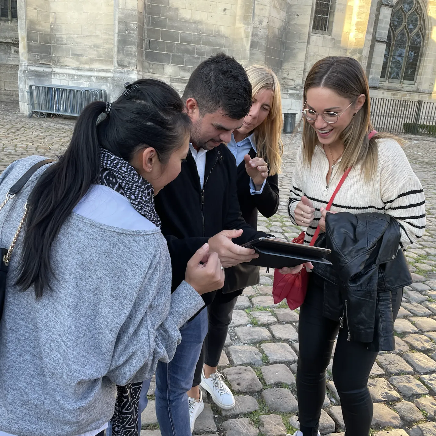 Equipe de collaborateurs qui regardent un téléphone pour poursuivre un rallye urbain