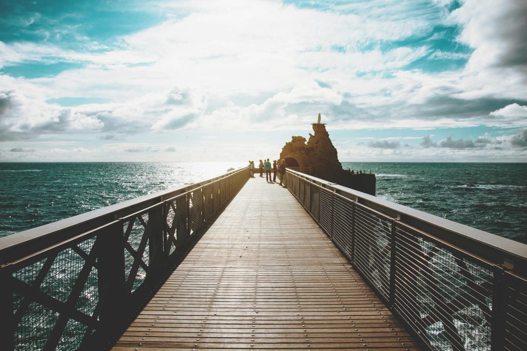 Photo représentant un pont en boit allant jusqu'au rocher de la vierge et avec la mer tout autour